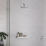 Caroma Luna chrome square overhead shower head in a tiled shower, wall-mounted with matching arm and shelf below