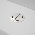Caroma round metal cistern flush button in brushed nickel, shown installed on a white toilet cistern