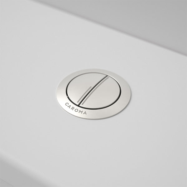 Caroma round metal cistern flush button in brushed nickel, shown installed on a white toilet cistern
