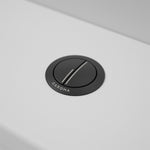 Caroma round matte black metal cistern flush button on a white toilet cistern lid, angled view