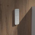 Caroma white bidet toilet remote control mounted on a wood-look wall panel