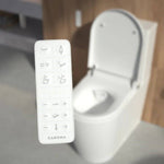 Caroma Urbane II bidet suite remote in front of white wall-faced toilet seat and pan, close-up lifestyle view