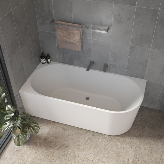 Caroma Urbane II white corner back to wall bath in modern tiled bathroom, oval acrylic tub with centre waste opening