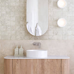 Caroma Urbane II matte black wall basin mixer above a white vessel basin in a modern bathroom vanity setting
