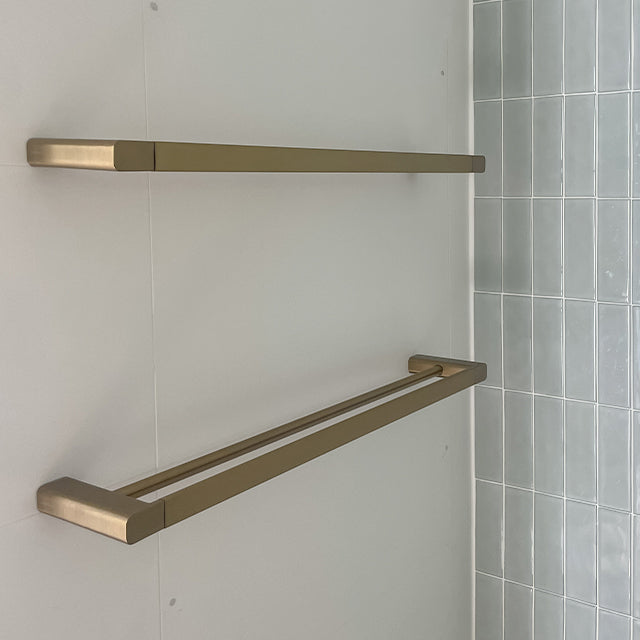 Caroma Urbane II double towel rail in brushed brass on a bathroom wall, showing two slim rails in a modern rectangular design