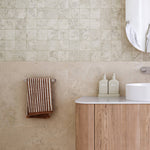 Caroma Urbane II chrome hand towel rail on beige tiled bathroom wall with towel hanging beside vanity