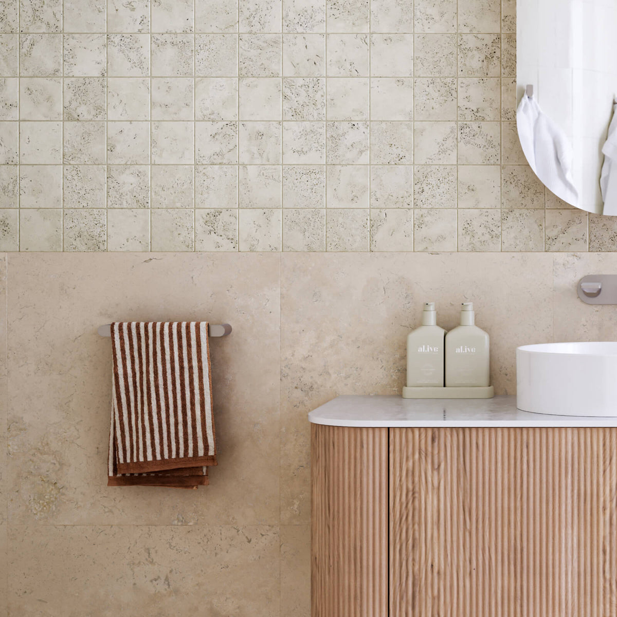 Caroma Urbane II chrome hand towel rail on beige tiled bathroom wall with towel hanging beside vanity