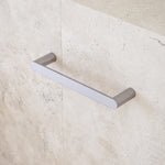 Caroma Urbane II chrome hand towel rail on a stone-look bathroom wall