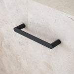 Caroma Urbane II matte black hand towel rail on beige stone bathroom wall