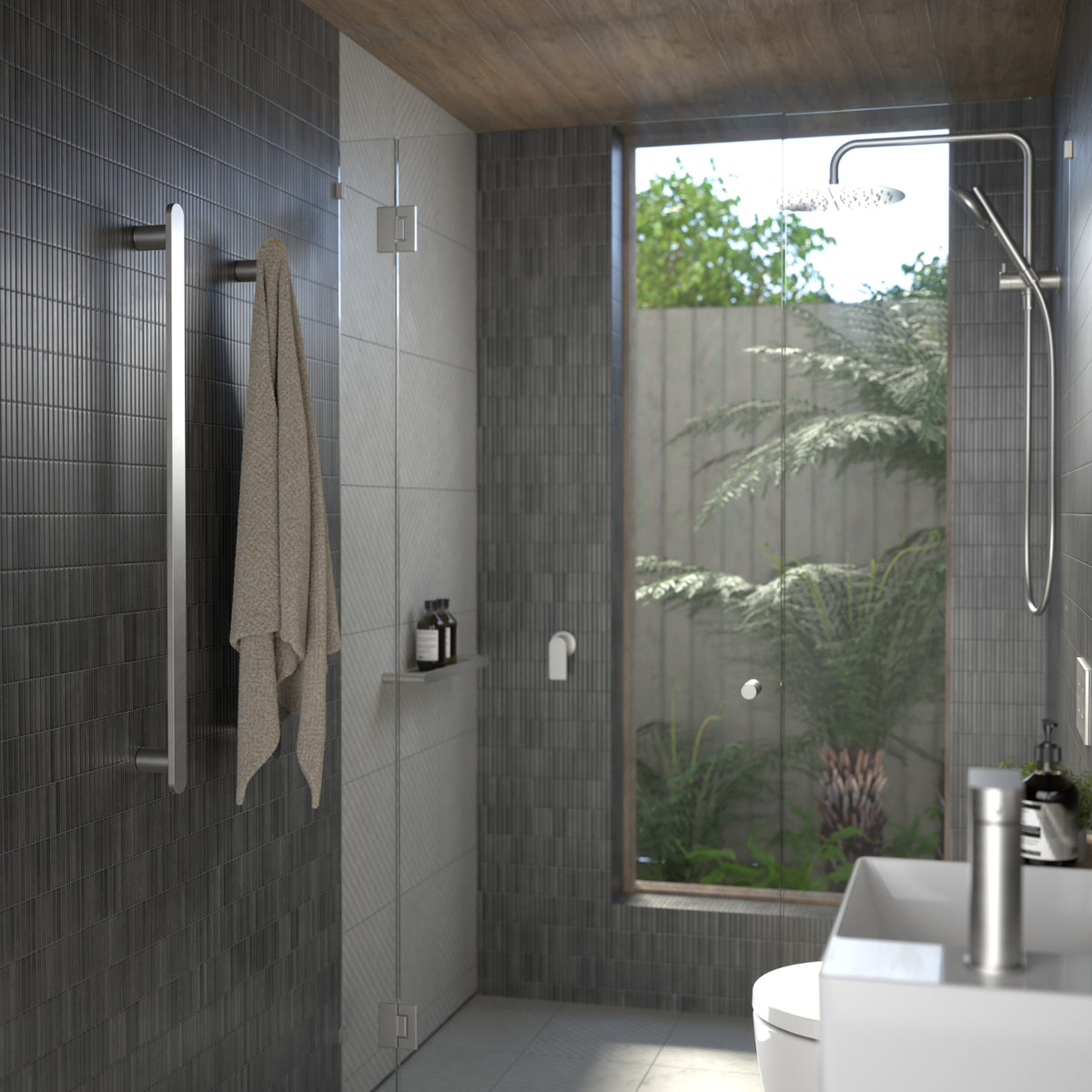 Caroma Urbane II vertical heated towel rail in polished stainless steel, shown installed in a modern bathroom with towel hanging on it