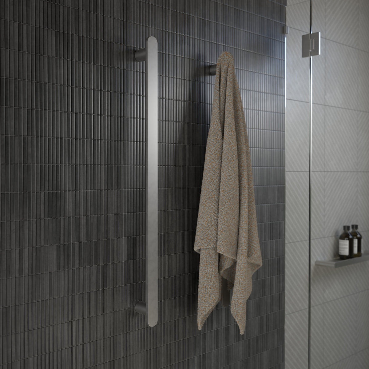 Caroma Urbane II vertical heated towel rail in polished stainless steel, mounted in a tiled bathroom with towel hanging on it