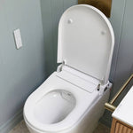 Caroma white wall-faced bidet toilet with raised seat open, remote control on wall, in bathroom setting