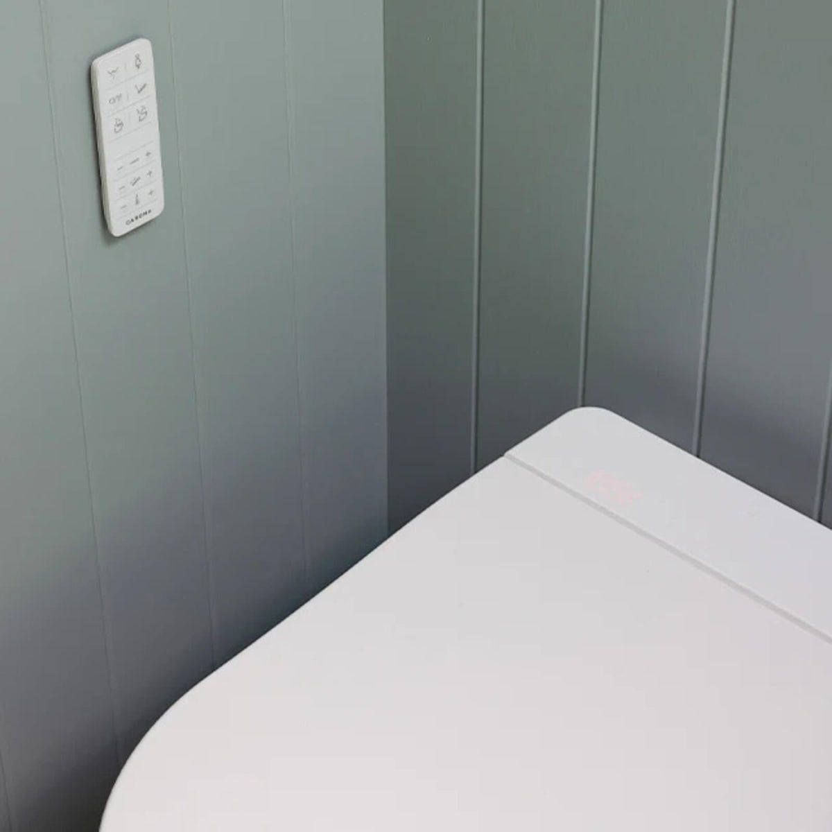 Caroma Urbane II white wall-faced bidet suite with remote control, shown close-up against grey panelled walls
