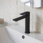 Caroma Urbane II mid tower basin mixer in matte black, shown installed on a bathroom basin sink.