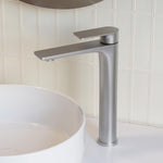 Caroma Urbane II tower basin mixer in brushed nickel, shown with a white vessel basin in a bathroom setting