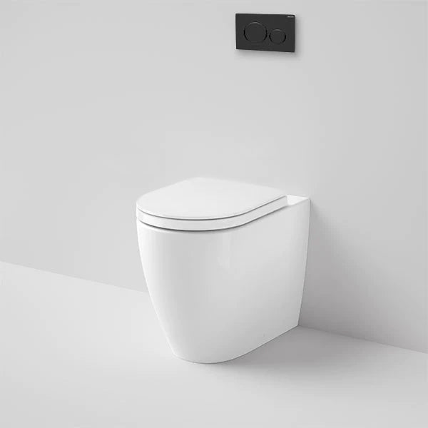 Caroma white wall-faced toilet pan with soft-close seat and black flush plate, front view against a grey wall