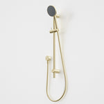 Caroma Urbane II rail shower in brushed brass with round handset and flexible hose on white wall