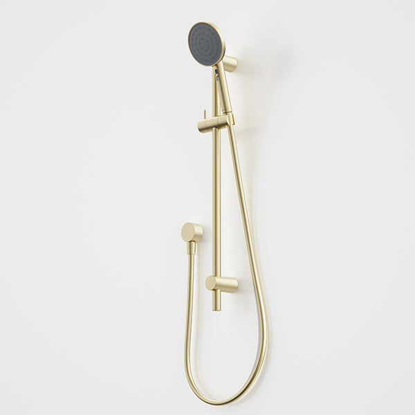 Caroma Urbane II rail shower in brushed brass with round handset and flexible hose on white wall