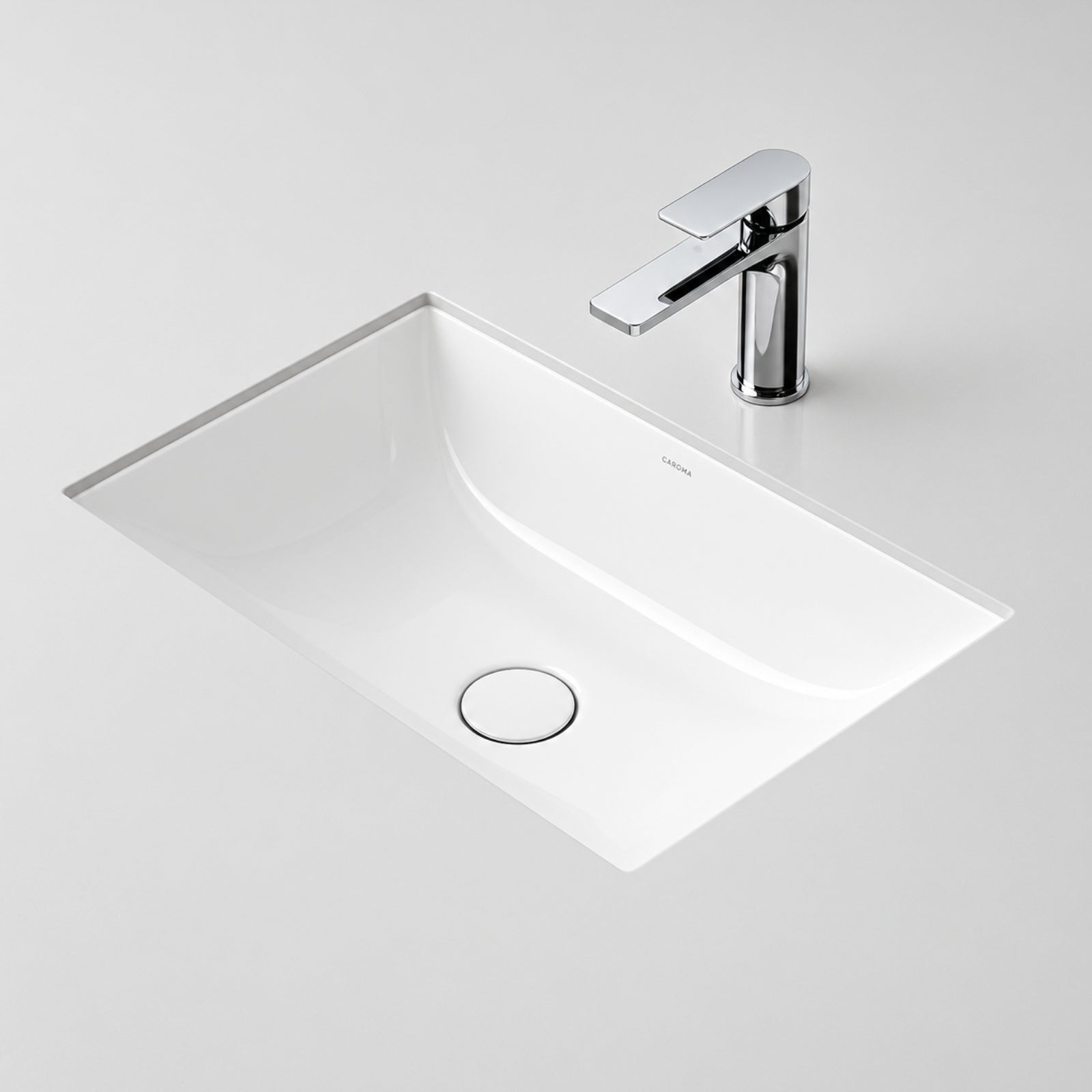 Caroma Urbane II white rectangular under counter basin with gloss ceramic finish and integrated waste, shown with chrome mixer tap
