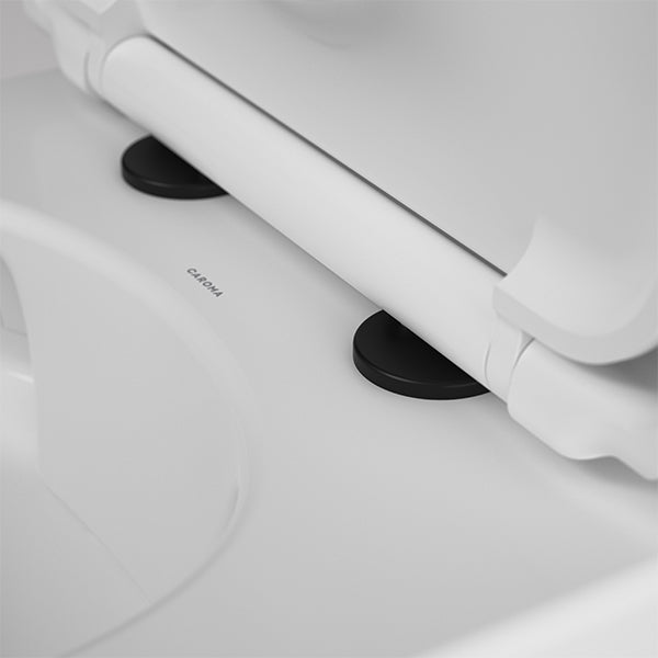 Caroma toilet seat hinge caps in matte black fitted to a white toilet seat, close-up detail view