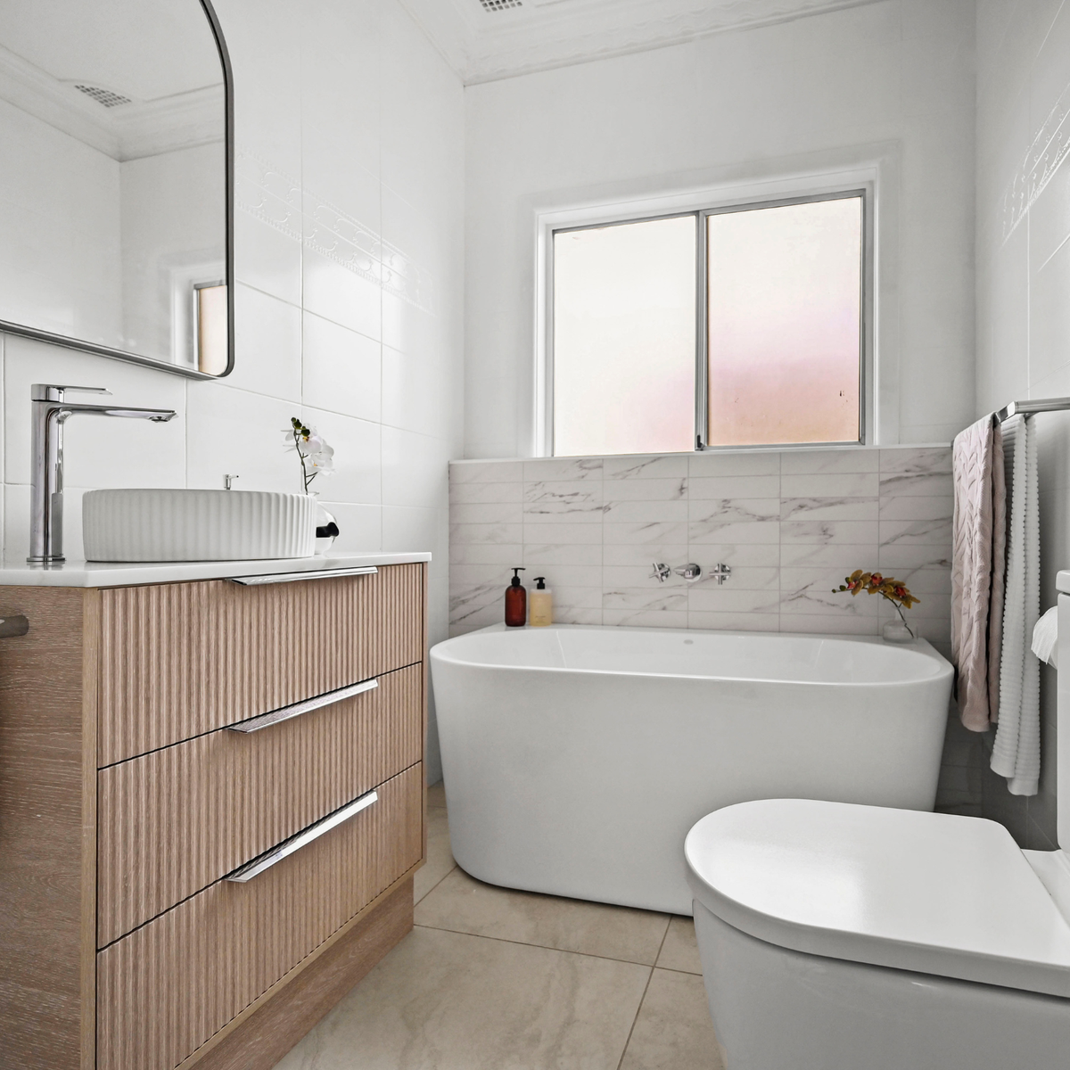 Chrome double towel rail in a modern bathroom, mounted beside a freestanding bath with towels hanging on the right