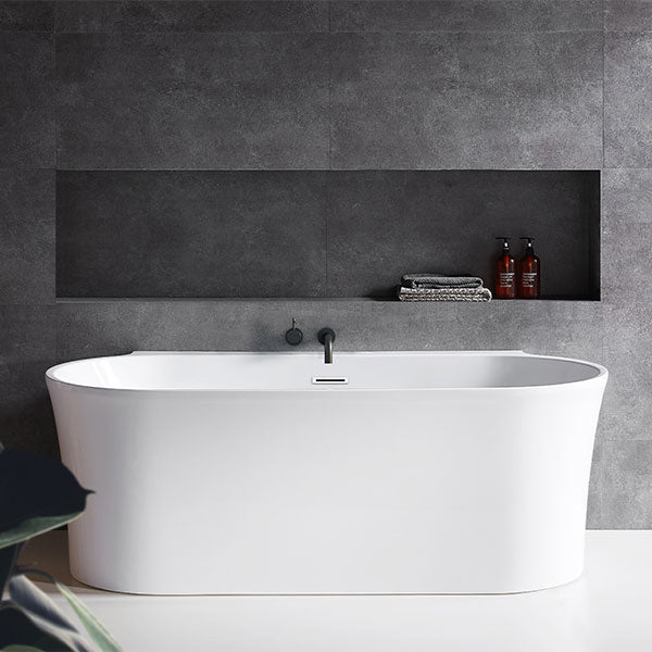 Decina Aurora back to wall bath in matte white, shown front on against a tiled bathroom wall with inset shelf.