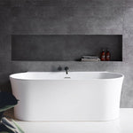 Decina Aurora back to wall bath in matte white, shown front on against a tiled bathroom wall with inset shelf.