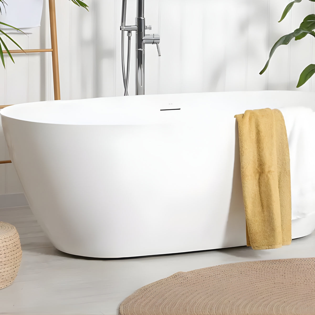 Decina Novara white freestanding oval bath in a styled bathroom, with integrated overflow and centre waste visible