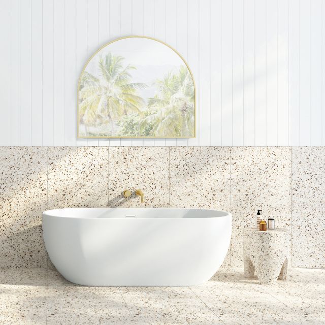 Decina Valentina freestanding bath in gloss white, oval shape, styled in a bright bathroom setting with wall art and speckled tiles