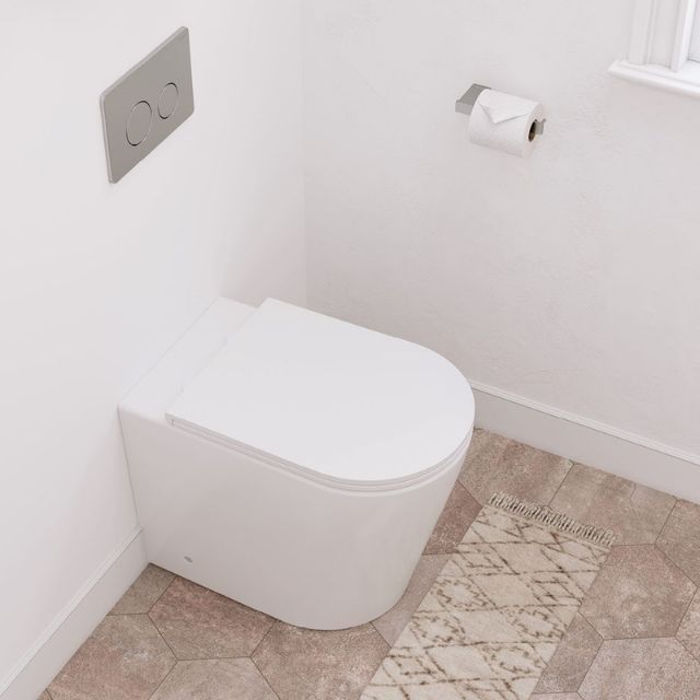 Fienza Aluca wall-faced toilet suite with slim white seat, shown installed against a white wall with flush plate and paper holder