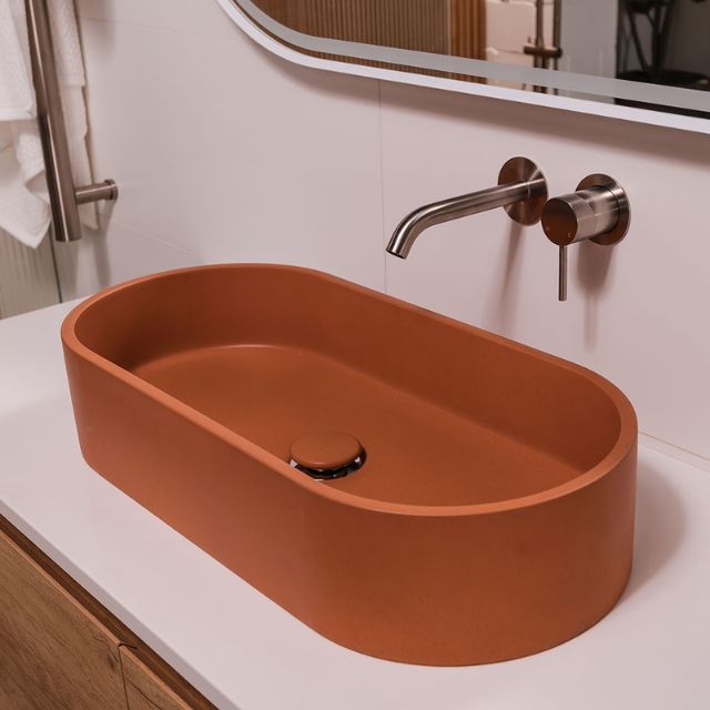 Fienza Jada Tuscan concrete pill above counter basin, oval shape, displayed on white vanity with wall-mounted tap and mirror丨
