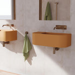 Fienza Kaya brushed copper wall basin mixer with round plate and curved outlet, shown in a modern bathroom with terracotta basins