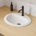 Fienza Kaya matte black basin mixer with curved outlet, shown installed on a white vanity basin in a bathroom scene