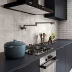 Fienza Kaya gun metal wall-mounted pot filler above a modern cooktop in a dark kitchen setting