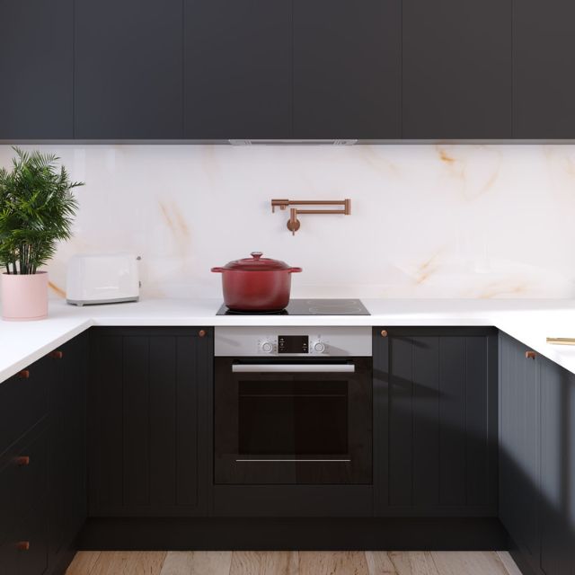 Fienza Kaya wall-mounted pot filler mixer in brushed copper above a cooktop in a modern black kitchen