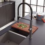 Fienza Kaya pull down sink mixer in gun metal, shown over a black kitchen sink with a high arched swivel spout and round lever handle