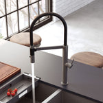 Fienza Kaya pull down sink mixer in gun metal, shown over a kitchen sink with flowing water and side lever control
