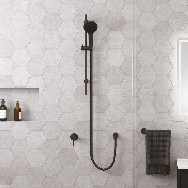 Fienza Kaya matte black rail shower with round hand shower, mounted in a tiled bathroom wall