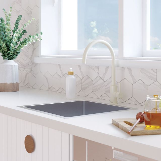 Fienza Kaya gloss warm white gooseneck sink mixer, hob mounted over a white kitchen sink and benchtop