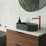 Fienza Kaya tall basin mixer in brushed copper, shown mounted beside a green vessel basin on a vanity