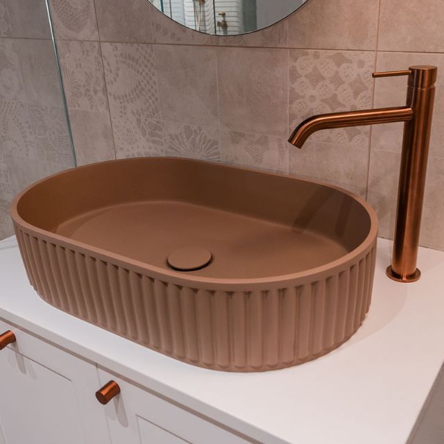 Fienza Kaya tall basin mixer in brushed copper, hob mounted beside an oval above-counter basin
