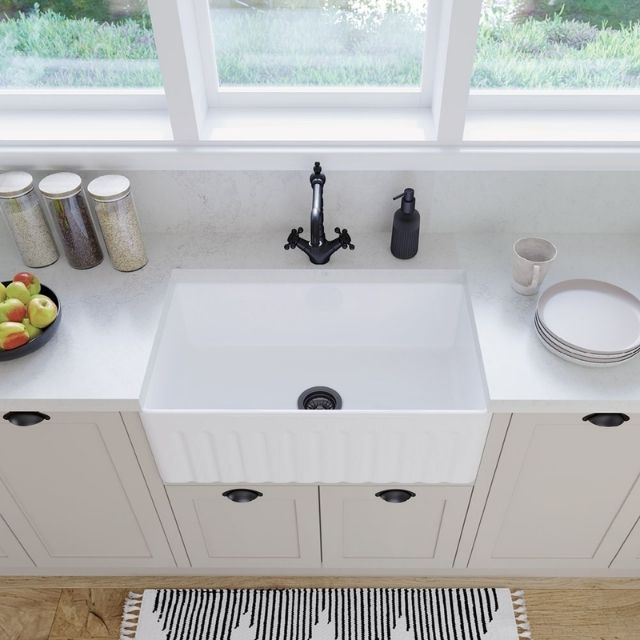 Fienza Olivia butler sink in gloss white, fluted-front apron sink shown in a bright kitchen with black tapware