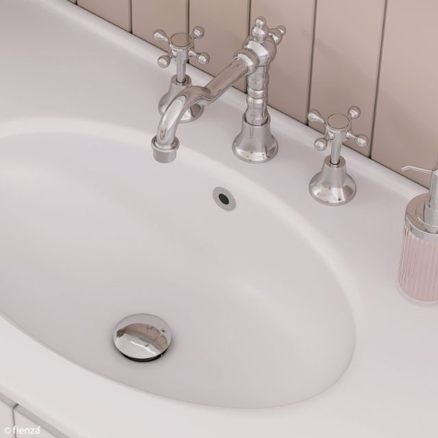 Fienza chrome pop-up basin waste in a white bathroom sink, with tapware above and drain plug visible