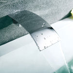 Fienza Vienna chrome waterfall bath outlet wall-mounted over a bath, shown pouring a wide cascading flow