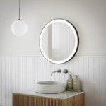 Ingrain round matte black framed frontlit LED mirror above bathroom vanity, wall hung with glowing edge in modern setting
