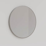 Ingrain round brushed nickel framed mirror, wall-mounted in a simple side view on a light wall