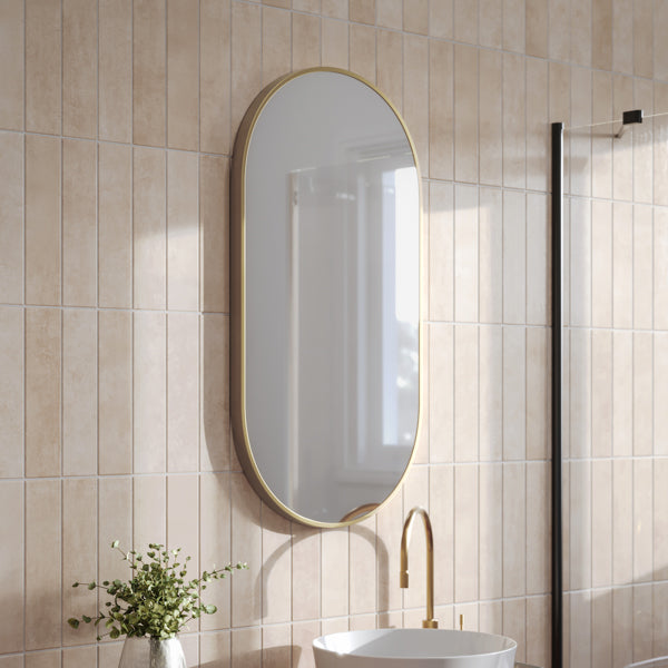 Ingrain pill-shaped wall mirror with brushed gold frame, portrait oval bathroom mirror on tiled wall