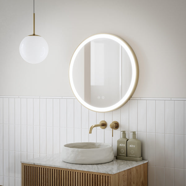 Ingrain round brushed gold framed frontlit LED mirror with touch controls, wall hung on a plain grey wall.