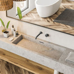 Nero Kara wall-mounted basin/bath set in gunmetal, shown over a concrete vanity with a wall spout and round handle.