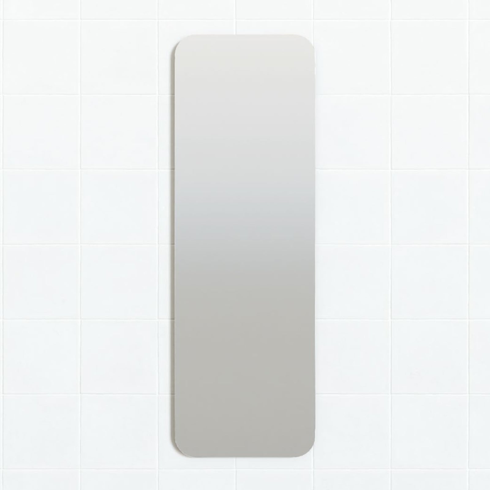 Marquis Alta frameless vertical mirror with rounded corners, mounted on white tiled wall